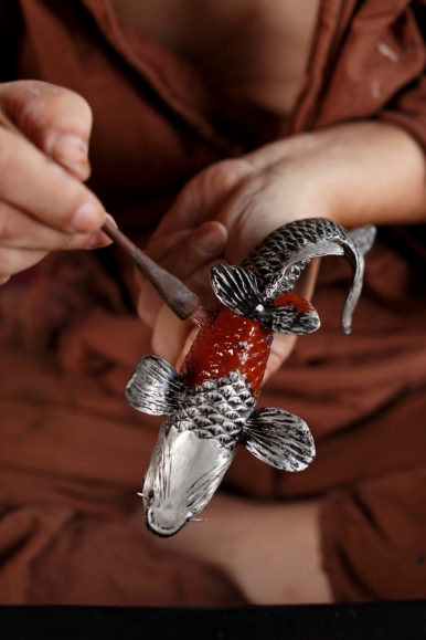 A Zohiko craftsman applying lacquer to the body of the cast pewter carp