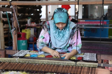 Weaving songket, a fabric made out of silk or cotton and intricately patterned with gold or silver threads