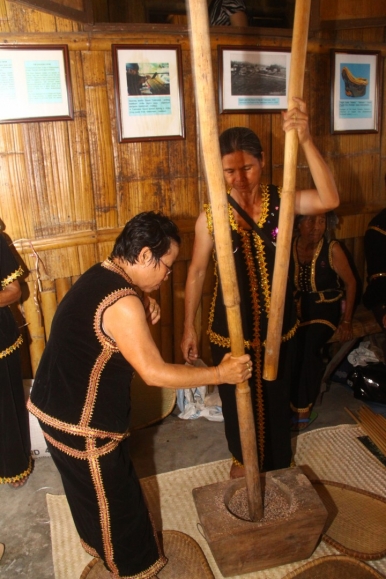 Women pounding paddy to dehusk the rice