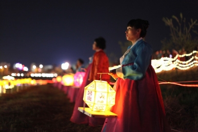 A woman carries a lantern decorated with Buddhist symbols