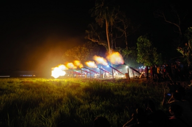 Spectators watch as the canons fire across the dark rice fields