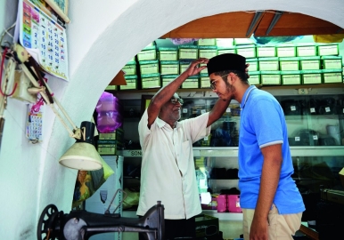 Haja Mohideen helps a young customer choose the right songkok