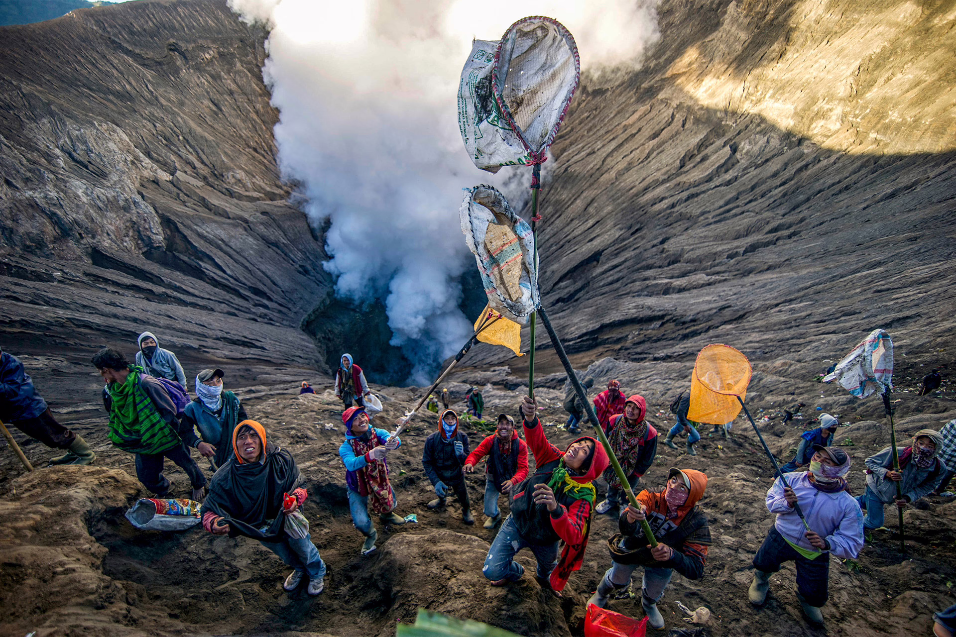 Some people prepare to catch offerings thrown by Tengger tribe people into the crater of Bromo volcano