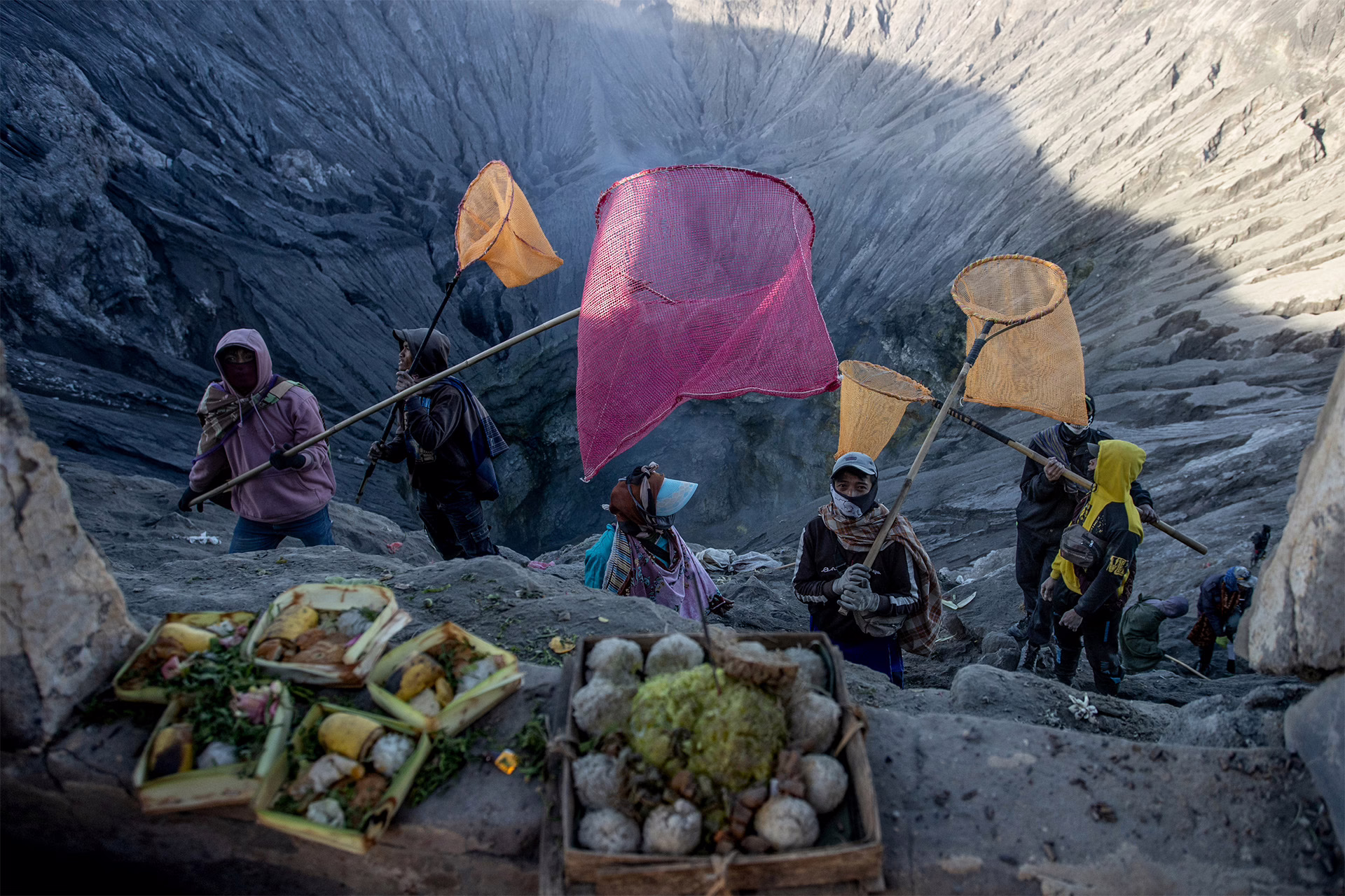 Indonesian men bring nets to catch offerings thrown into the crater by Tenggerese worshippers